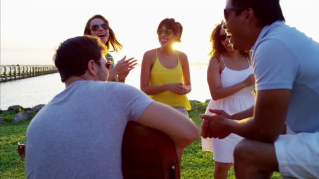 Multi-ethnic-people-with-guitar-dancing-on-beach