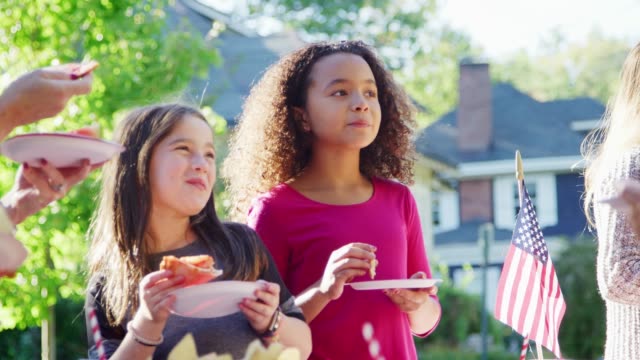 Mädchen-stehen-Essen-Pizza-mit-Nachbarn-auf-einen-Block-party