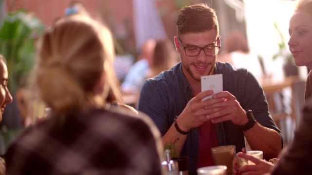 Mensajes-de-texto-de-hombre-feliz-hipster-en-smartphone-mientras-que-en-un-café
