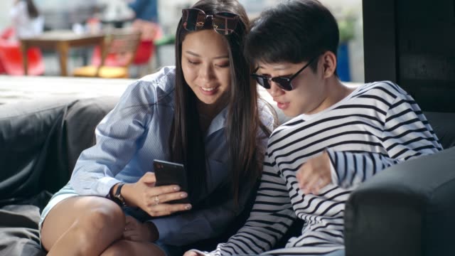 Joven-pareja-asiática-Ver-Video-en-Smartphone-en-el-café-al-aire-libre
