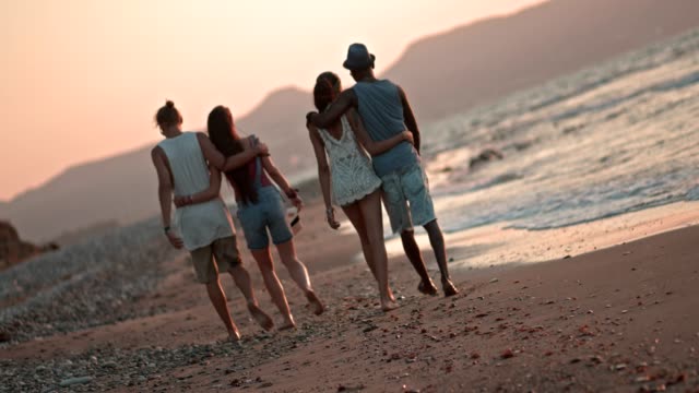 Romantische-multiethnischen-Hipster-Paare-zu-Fuß-am-Strand-bei-Sonnenuntergang