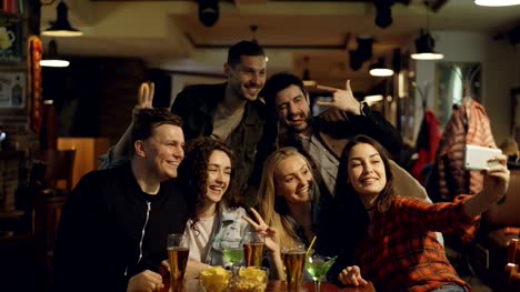 Happy-young-people-in-casual-clothes-are-taking-selfie-in-bar.-They-are-posing,-making-silly-faces,-laughing-and-gesturing.-Funny-photos-for-good-memories-concept.