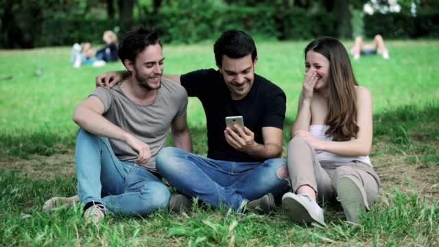 Gruppe-von-Freunden-im-Park,-lachen,-Blick-auf-das-smartphone
