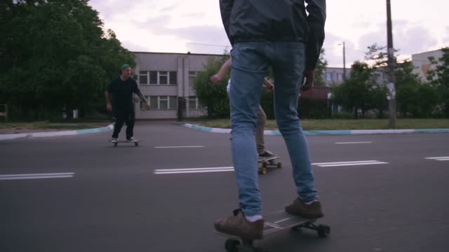 Group-of-young-people-skateboarding-on-the-road-in-the-early-morning,-cinematic-shot,-slow-motion