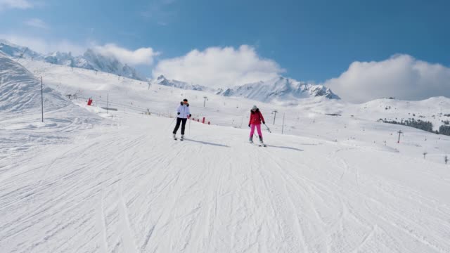 Dos-esquiadores-de-mujer-esquí-abajo-de-la-pendiente-Ideal-de-la-montaña-en-invierno