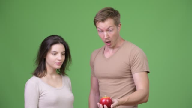Young-couple-looking-surprised-at-apple-together