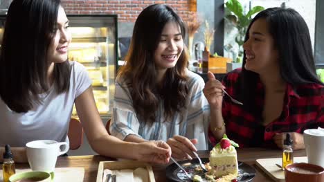 Freundesgruppe-von-drei-asiatischen-Frauen-genießen-einen-Erdbeerkuchen-und-ein-Gespräch-im-Café-und-restaurant