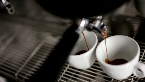 Super-Slow-Motion-von-heißen-Espresso-Kaffee-Gießen-in-ein-zwei-weiße-Porzellantassen-aus-Kaffeemaschine-in-4k-(Draufsicht-Nahaufnahme)