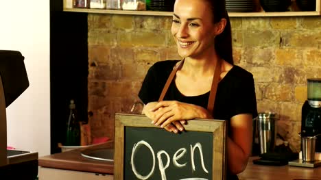 Ein-Coffee-Shop-Arbeiter-hält-ein-Schild-\"geöffnet\".