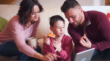 Glückliche-Familie-mit-digital-Tablette-mit-Pizza-im-Wohnzimmer