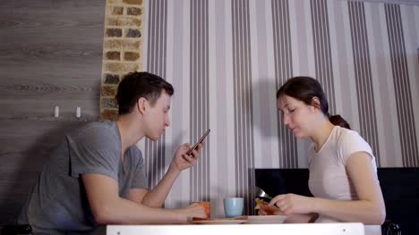 Young-man-with-phone-and-woman-eating-at-table
