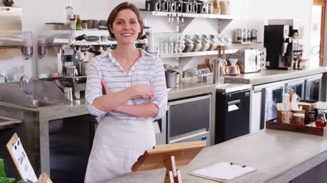 Weibliche-Coffee-Shop-Besitzer-stützte-sich-auf-Zähler-im-Coffee-shop