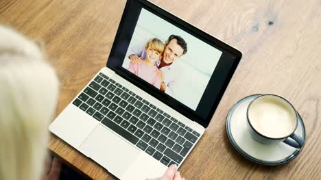 Attractive-Blond-Woman-Flicking-Through-Family-Album-On-Laptop