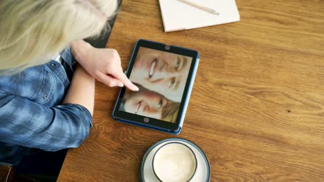 Attractive-Blond-Woman-Swiping-Through-Family-Album-On-Digital-Tablet