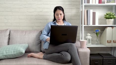 hermosa-mujer-trabajando-en-ordenador-portátil-sentado-en-el-sofá