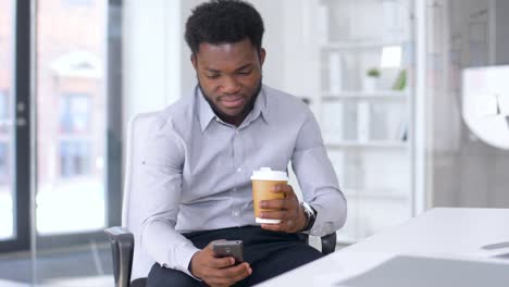 Geschäftsmann-mit-Smartphone-und-Kaffee-im-Büro