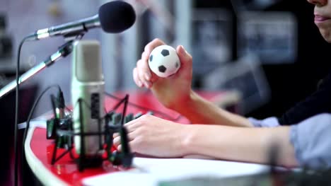 Man-behind-microphone-taps-toy-ball-and-talks.