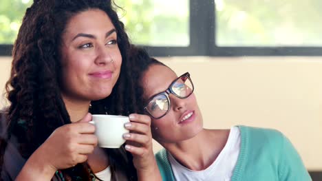 Lesbiana-sonriente-pareja-bebiendo-café-juntos