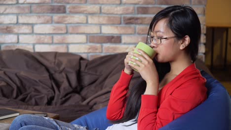 Young-woman-drinking-tea-from-green-mug-in-cafe