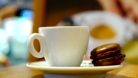 Eine-Tasse-Kaffee-mit-braunem-macaron-in-einem-überdachten-café