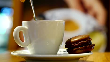 Eine-Tasse-Kaffee-mit-braunem-macaron-in-einem-überdachten-café
