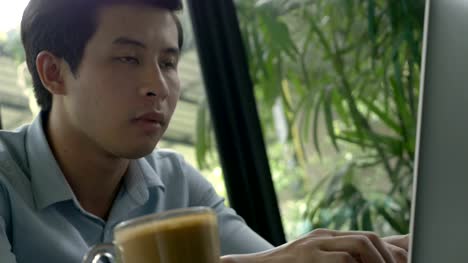 4K:-junge-asiatische-Geschäftsmann-mit-Laptop-im-Café-Kaffee
