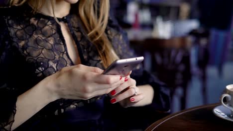 junge-nette-Frau-mit-Telefon,-sitzen-in-einem-Café-eine-Smartphone-halten,-Texte-zu-beantworten.-Schöne-Geschäftsfrau-in-einem-Restaurant-in-der-Mittagspause-Surfen-Nachrichten-online