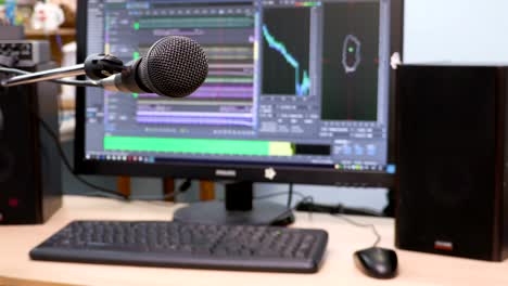 Microphone-on-the-background-of-the-computer-monitor.-Home-recording-Studio.-Close-up.-The-focus-in-the-foreground.-Blurred-background.-Software-for-recording-and-editing-sounds.-4K,-UHD,-Ultra-HD