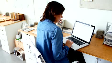 Female-executive-sitting-at-desk-and-using-laptop