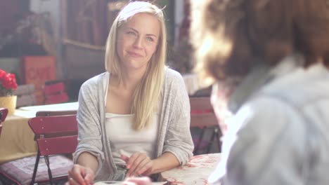 Zwei-Mädchen-sind-Talking-in-Outdoor-Coffee-Shop