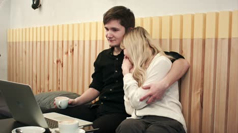 Schöne-junge-Paar-mit-Laptop-im-Café,-sie-sind-Film-und-trinken-Kaffee-zusammen