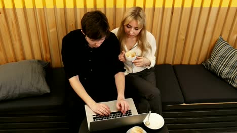 Hipster-couple-sitting-incafe-drinking-coffee-using-laptop