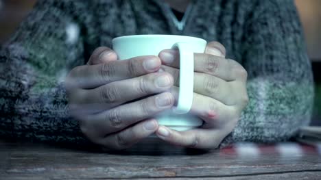 Frau-Hand-hält-eine-Tasse-Kaffee-im-Café-in-den-regnerischen-Tag