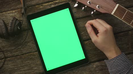 Músico-con-Tablet-PC-con-pantalla-verde-en-el-modo-de-retrato.-Vista-superior.-Estilo-de-vida-causal