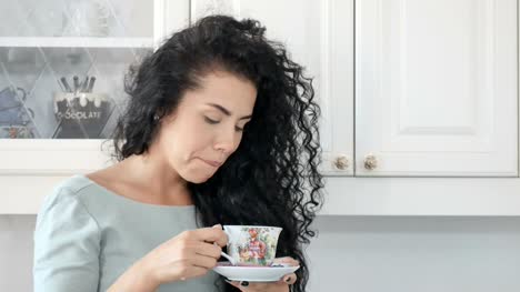 Smiling-woman-drinks-coffee-in-the-kitchen