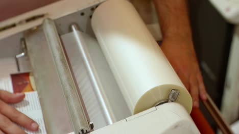 Hands-of-white-man-run-a-roll-laminator-during-its-work.-Closeup-view