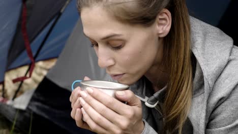 Woman-drinking-hot-beverage-in-camping-tent.-Couple-people-in-love-autumn-outdoor-trip-in-nature.-Fall-sunny-day.-4k-slow-motion-video