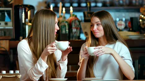 Two-young-female-friends-meeting-in-cafe
