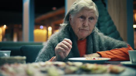Schöne-ältere-Frau-sitzt-im-Restaurant-und-Pizza-isst.-Frau-schneidet-die-Pizza-in-Stücke-im-café