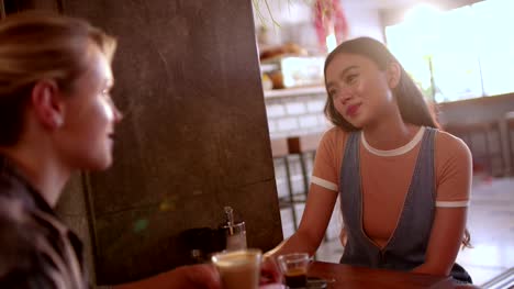 Young-multi-ethnic-hipster-women-talking-and-drinking-coffee-at-cafe