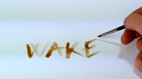 Hand-mit-Kaffee,-schreibt-das-Wort-aufwachen