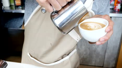 Close-up-hand-of-barista-making-latte-art-at-cafe.