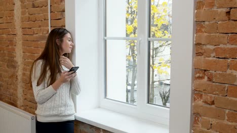 Schöne-Frau-Kaffee-trinken-mit-Smartphone-im-modernen-Loft-Büro