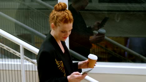 Businesswoman-using-mobile-phone-while-moving-downstairs-4k