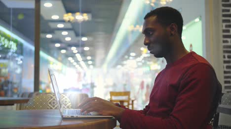 Porträt-von-glücklich-afrikanischen-Geschäftsmann-in-einem-Café-sitzen-und-arbeiten-am-laptop