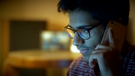 Close-up,-Beautiful-Indian-Man-In-Glasses-Speaks-Over-Phone-And-Looks-At-Computer-Screen