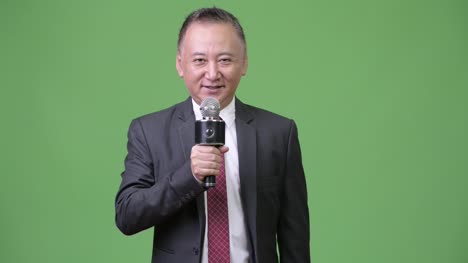 Mature-Japanese-businessman-using-microphone
