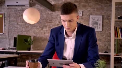 Young-serious-businessman-is-watching-in-tablet,-drink-coffee,-communication-concept,-business-concept