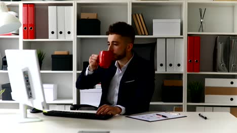 Jungunternehmer-am-Computer-arbeiten-und-Kaffee-trinken