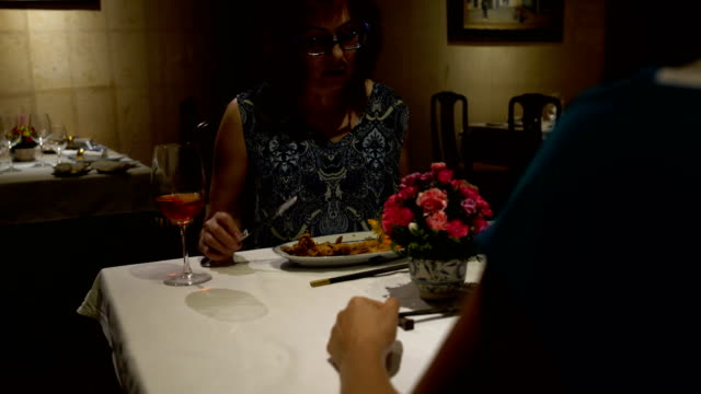 Im-Restaurant-eine-Frau-an-einem-Tisch-sitzen,-Essen,-reden,-Gläser-Klirren-und-Rotwein-trinken